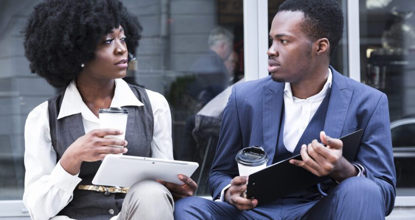 portrait young african businessman businesswoman sitting together outside office ()